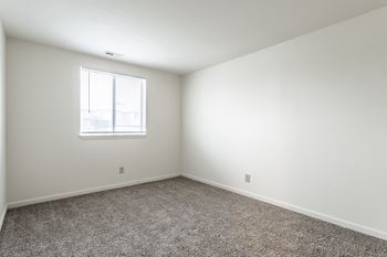A room with a carpeted floor and a window.